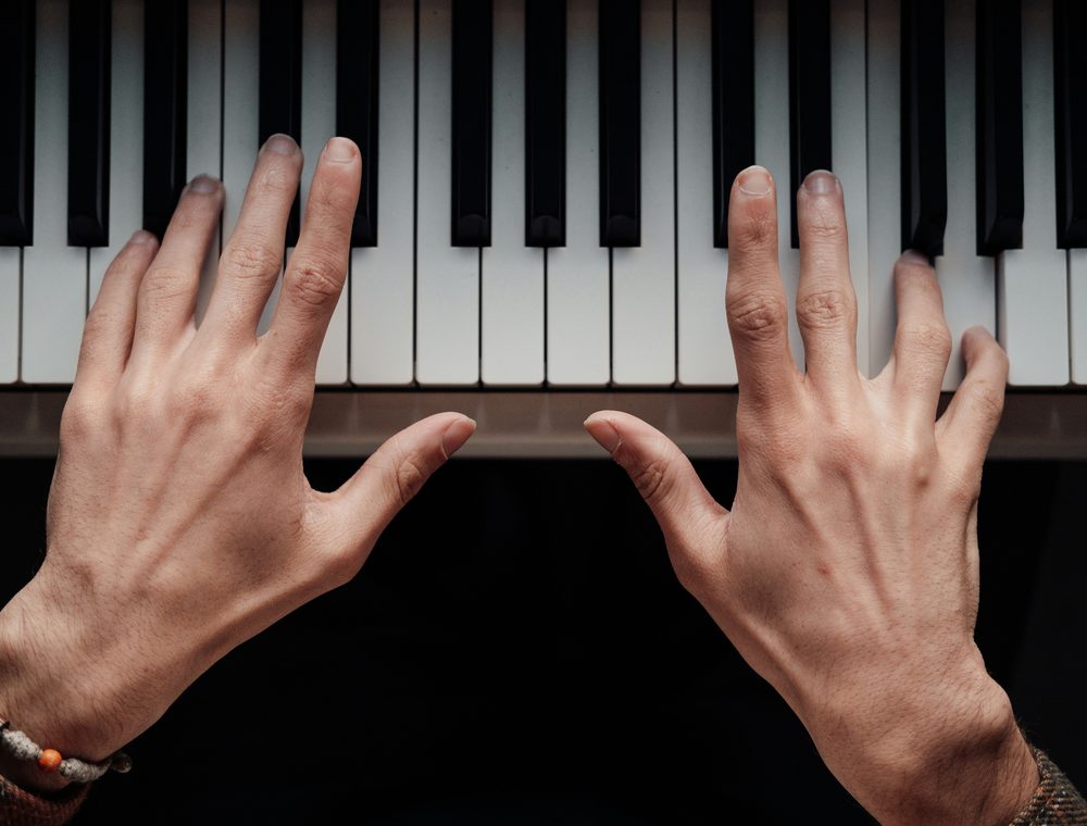 Hands playing across the keys of a piano