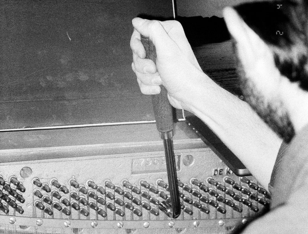 A piano technician at work, photographed in black and white
